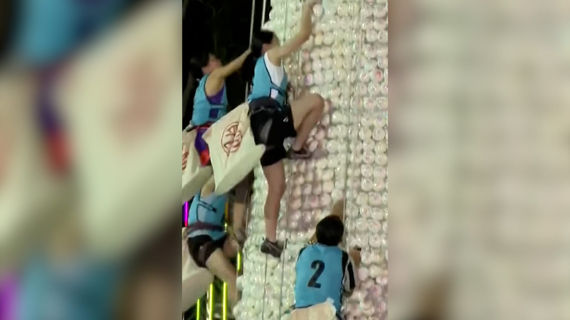 شاهد.. متنافسون يتسلقون قمة برج شاهق زُين بالكعك البلاستيكي